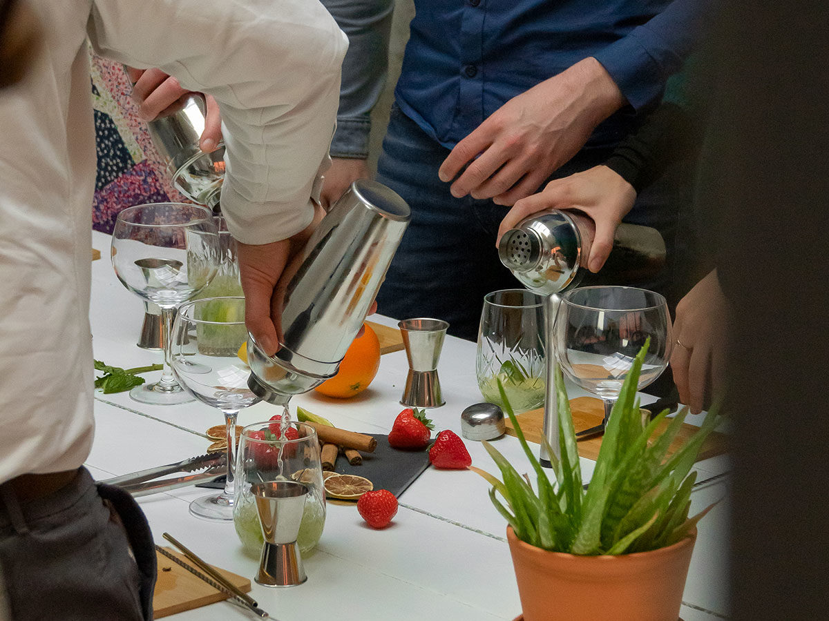 Table contenant différentes choses destinées à la préparation de cocktails : alcools, shakers, fraises, cannelle, doseur, mélangeur, etc.