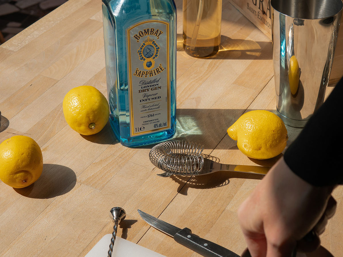 Ingrédients destinés à la préparation de cocktails : citron et Bombay Saphire sur une table disposant d'un couteau et d'un shaker