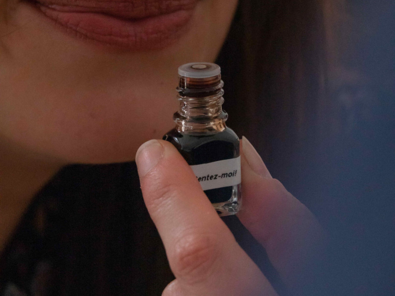 Participant du Casino des sens occupé à sentir une fiole contenant du liquide