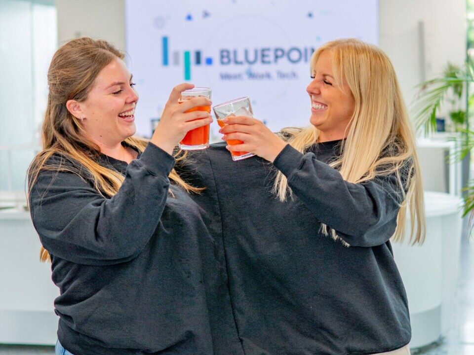 Deux femmes dans un même pull et levant un verre lors d'une animation teambuilding