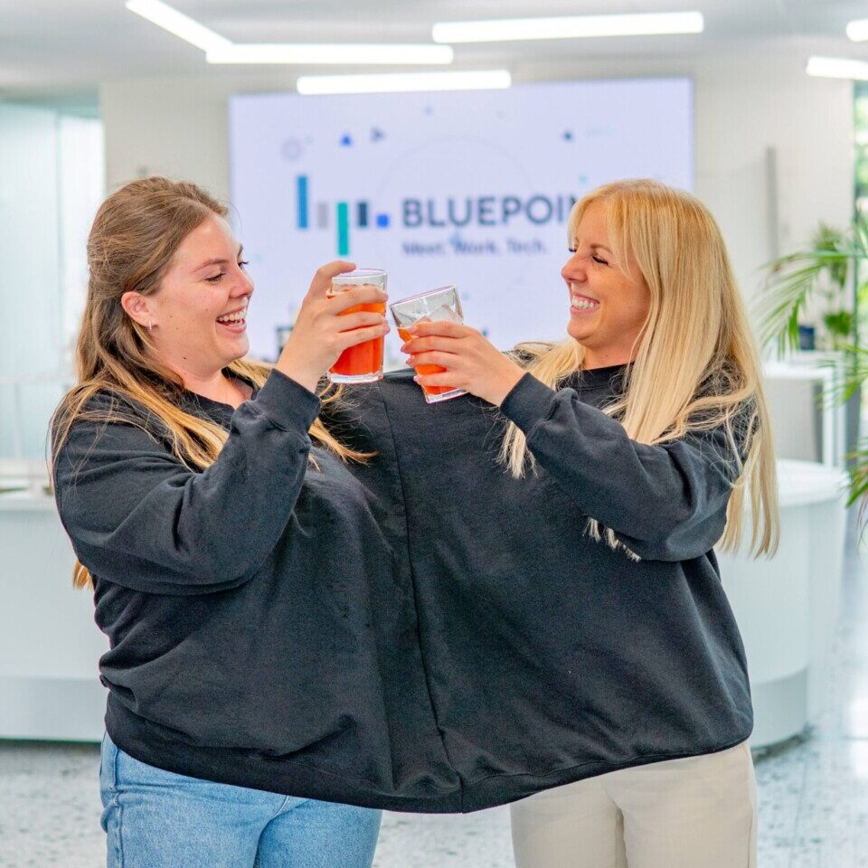 Deux femmes dans un même pull et levant un verre lors d'une animation teambuilding