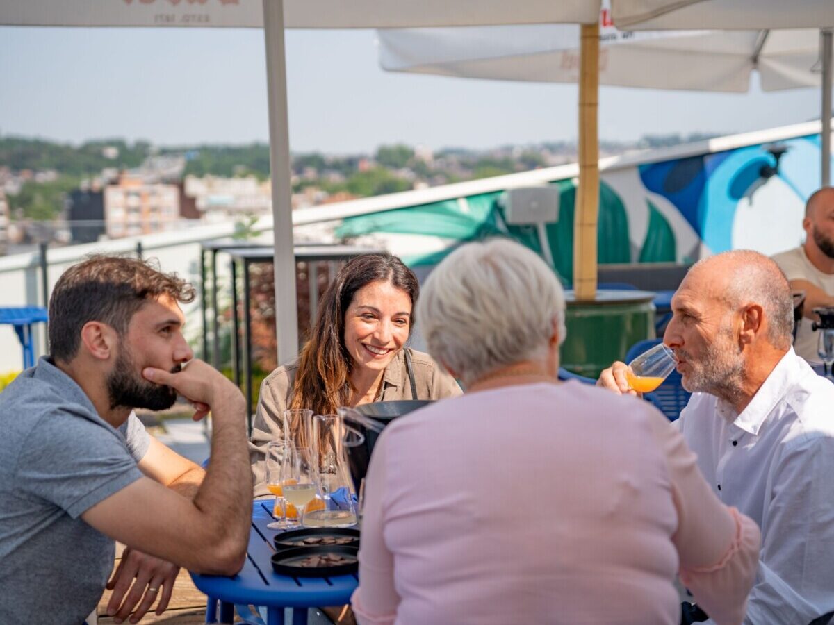 Hommes et femmes attablés au soleil et profitant d'une dégustation de jus de fruits