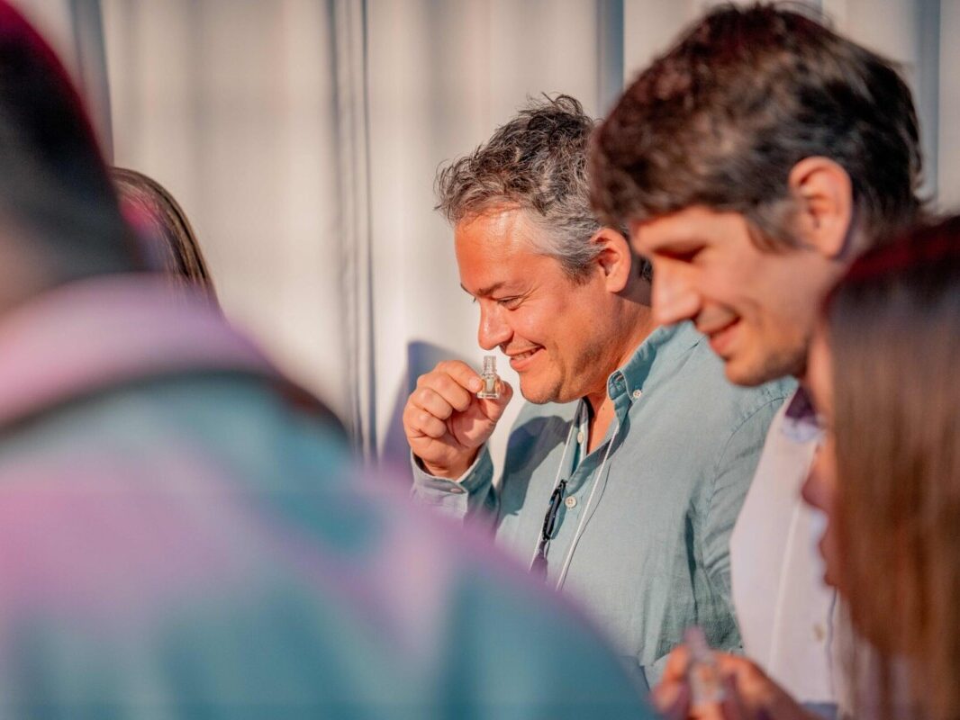 Deux hommes souriants en train de renifler les arômes d'un vin lors d'un atelier vin