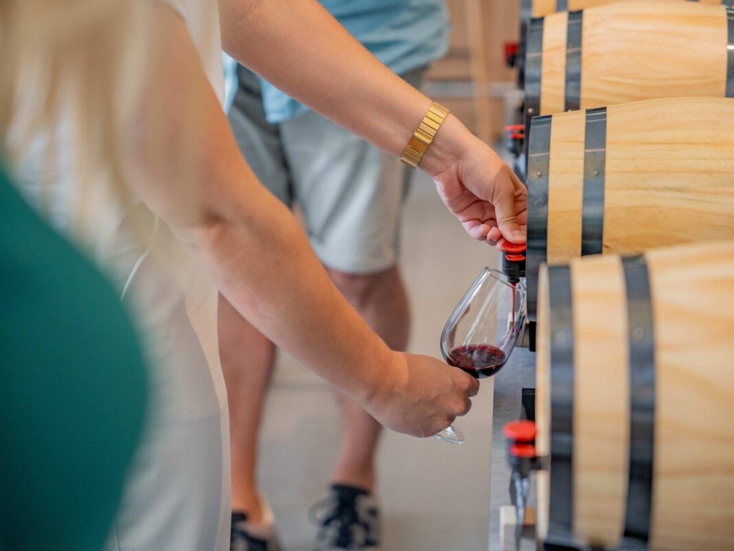 Personne se servant un verre de vin rouge à un tonneau de vin