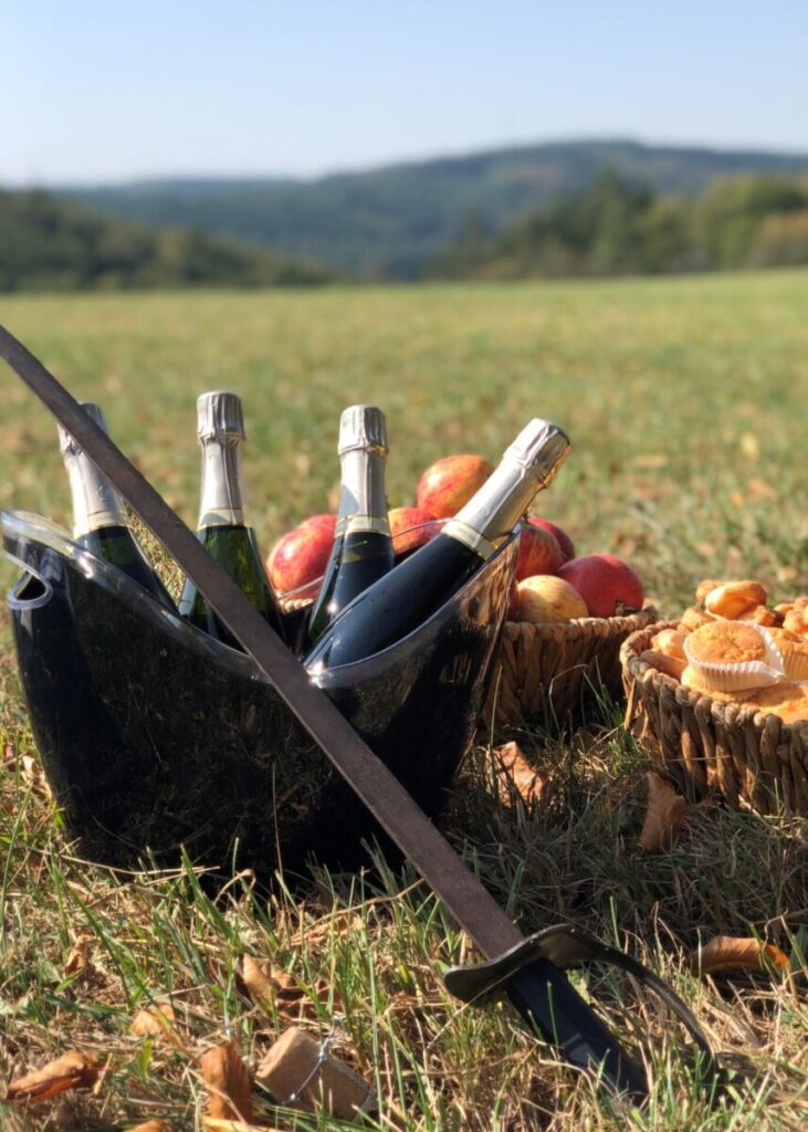 Panier avec des bouteilles de bulles et le sabre pour les sabrer dans un champ